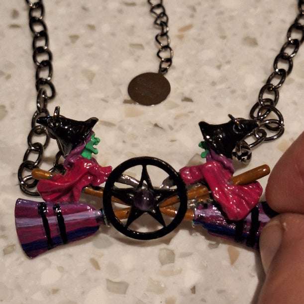 Colorful witch on a broomstick charm on a chain against a neutral background