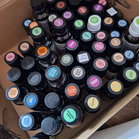 Box filled with various small bottles with colorful labels on a wooden surface.