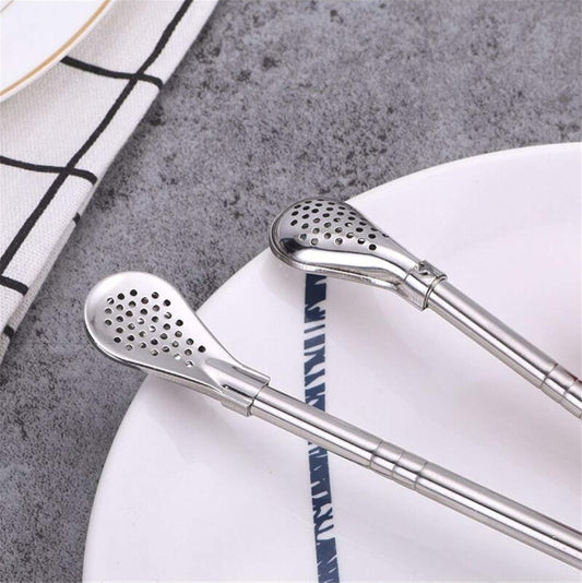 Two metal straws with perforated ends on a white plate with blue stripes.