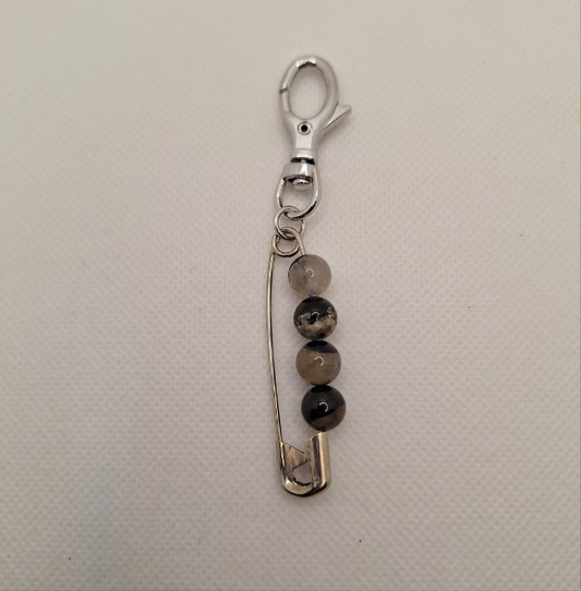 Keychain with safety pin and beads on a beige background