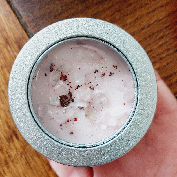 Close-up of a small container with a pink wax inside on a wooden surface