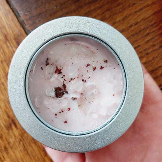 Close-up of a small container with a pink wax inside on a wooden surface