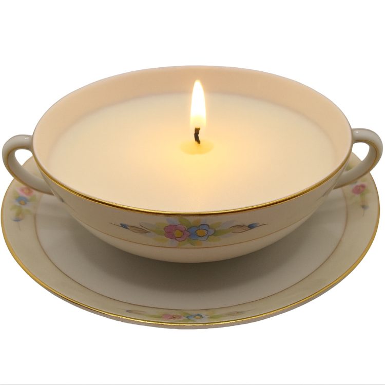 Candle in a decorative soup bowl with floral patterns on a white background
