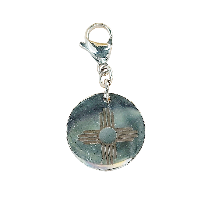 Round charm with a silver sun design on a white background