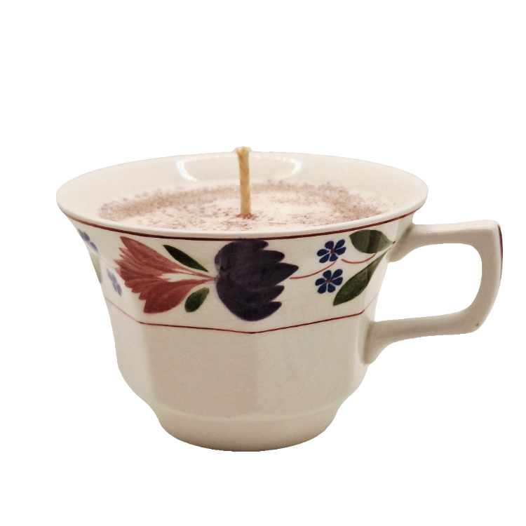 Ceramic mug with floral design filled with a candle on a white background