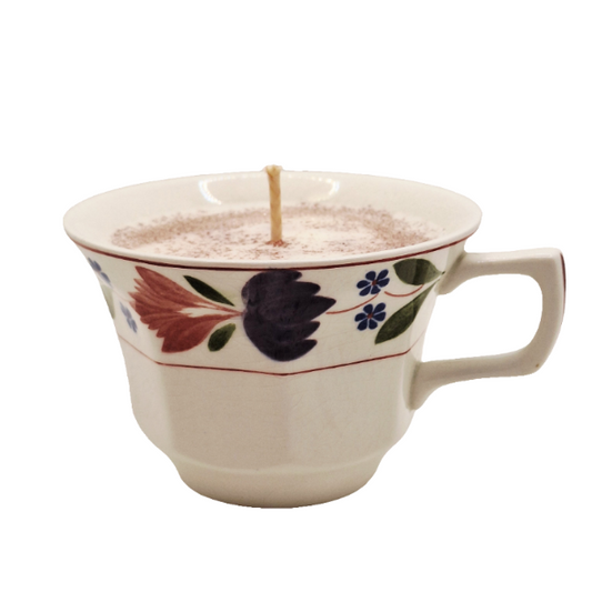 Ceramic mug with floral design filled with a candle on a white background
