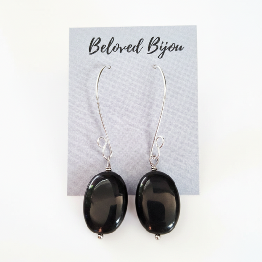 Black oval obsidian earrings on a Beloved Bijou card with a white background