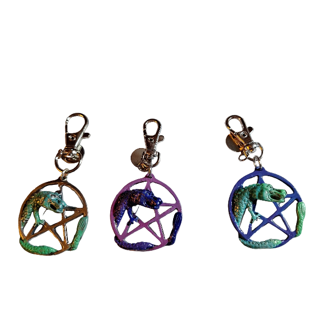 Three colorful pentacle charms with dragon designs on a white background