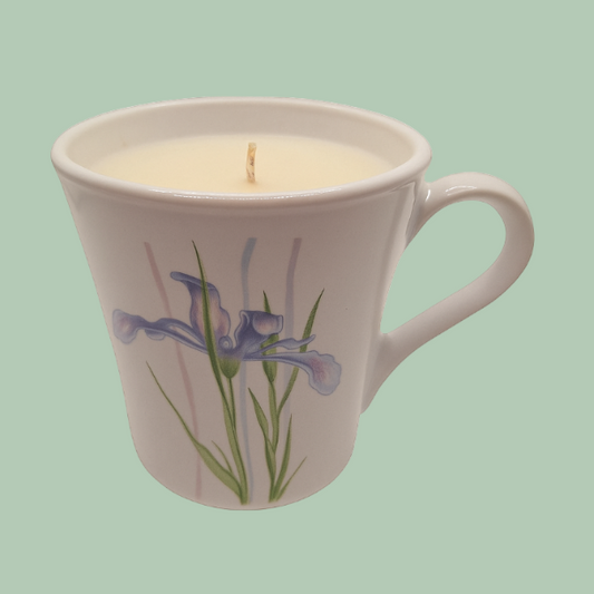 Candle in a mug with floral design on a light green background