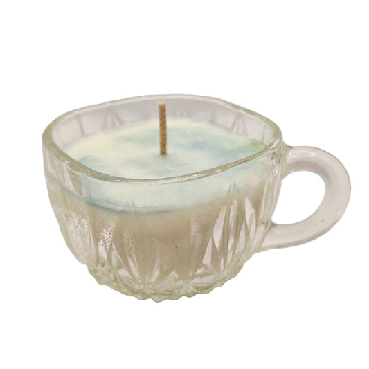 Candle in a faceted glass cup on a white surface