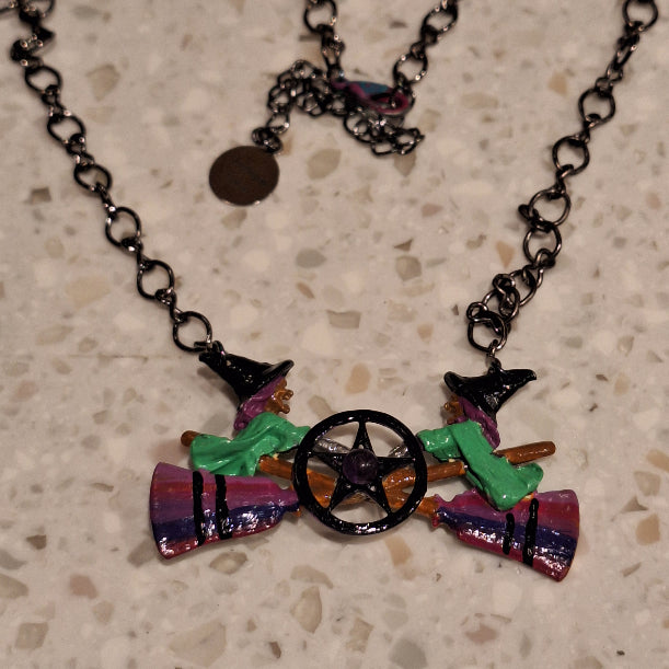 Colorful witch-themed necklace on a textured surface