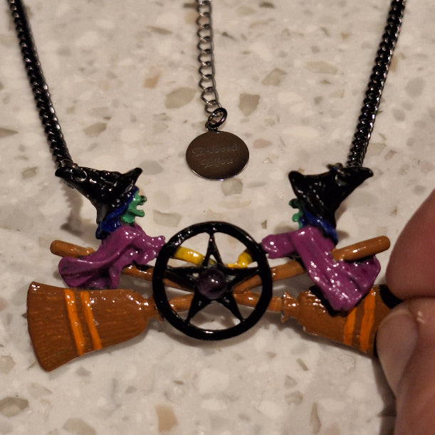 Colorful broom with witch hat and cat on a chain against a textured surface