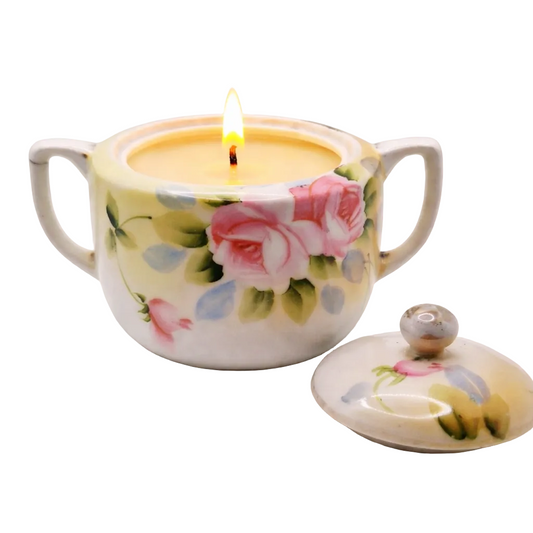 Floral-patterned ceramic container with a lit candle inside on a white background