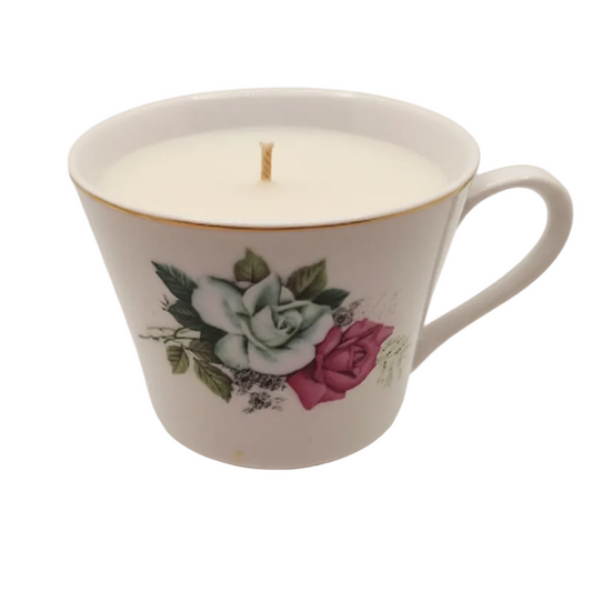Candle in a decorative teacup with floral design on a white background