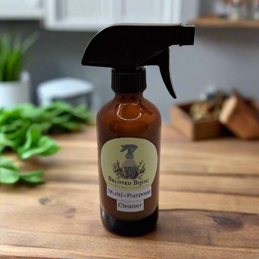 Brown spray bottle labeled 'Beloved Bijou' on a wooden surface with a blurred kitchen background.