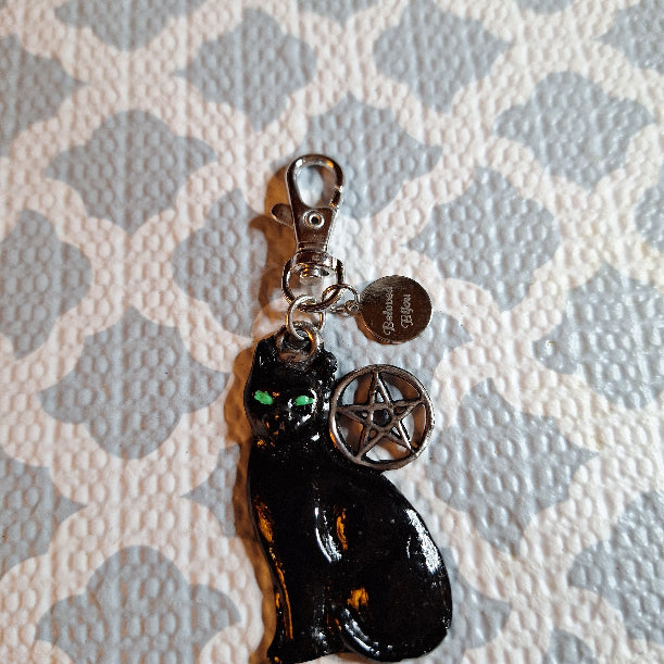 Black cat-shaped charm with pentacle on a textured surface