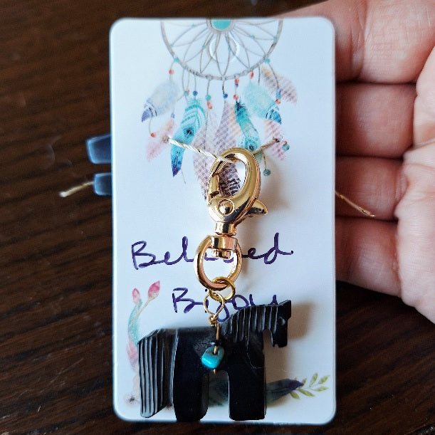 Black carved horse charm with gold clasp on a white card with 'Beloved Bijou' text