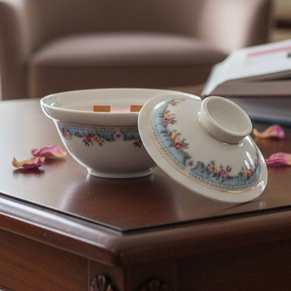 Decorative ceramic bowl soy wax candle with a lid and with floral patterns on a wooden surface.