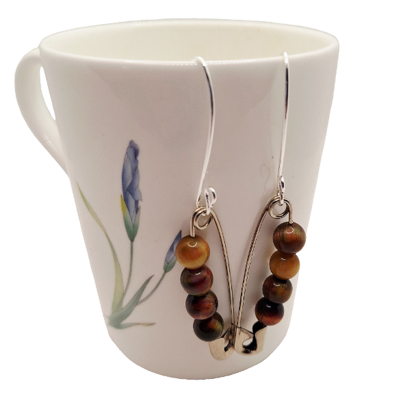 Pair of beaded earrings hanging from a mug with floral design