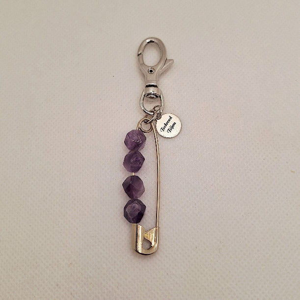 Keychain with purple amethyst beads and a safety pin on a beige background