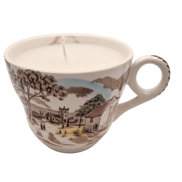 Ceramic cup with scenic design containing a candle on a white background