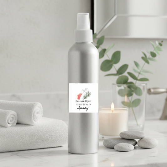 Silver spray bottle with a label on a bathroom counter with towels, candle, and plants.