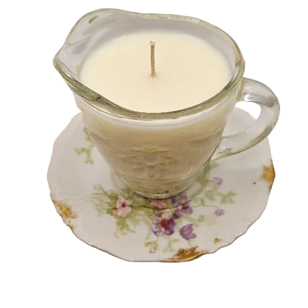 Candle in a glass container on a decorative saucer with floral design