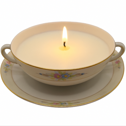 Candle in a decorative soup bowl with floral patterns on a white background