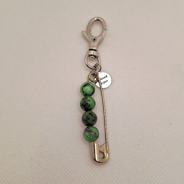 Keychain with green ruby in zoisite beads and a safety pin on a beige background