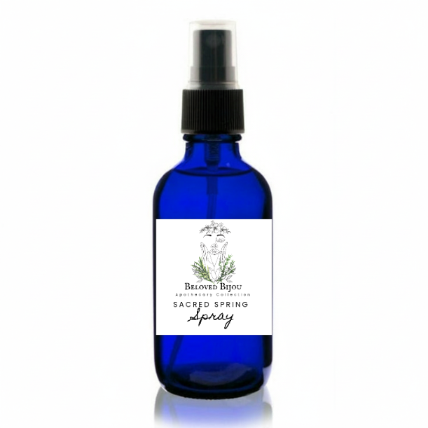 Blue spray bottle labeled 'Sacred Spring Spray' on a white background