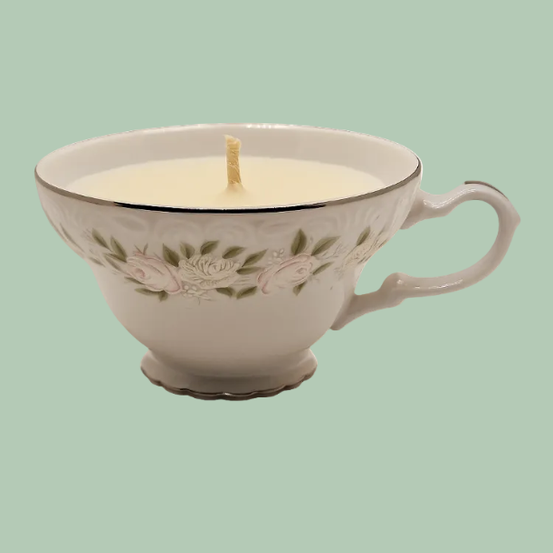 Teacup candle with floral design on a light green background