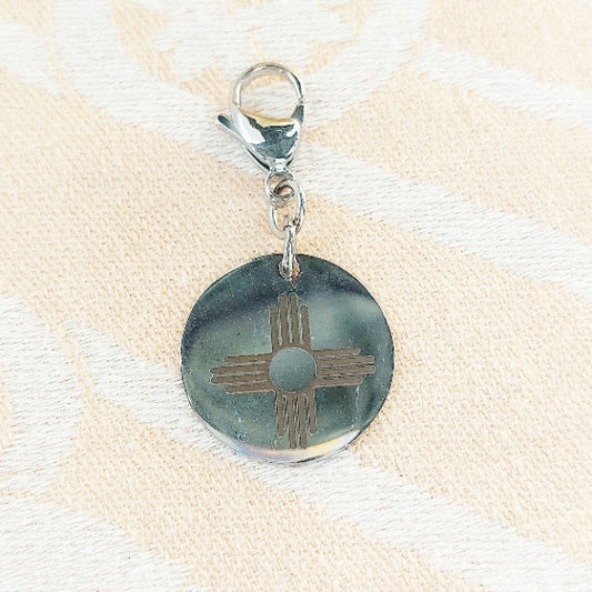 Round zia pendant with a design on a beige fabric background