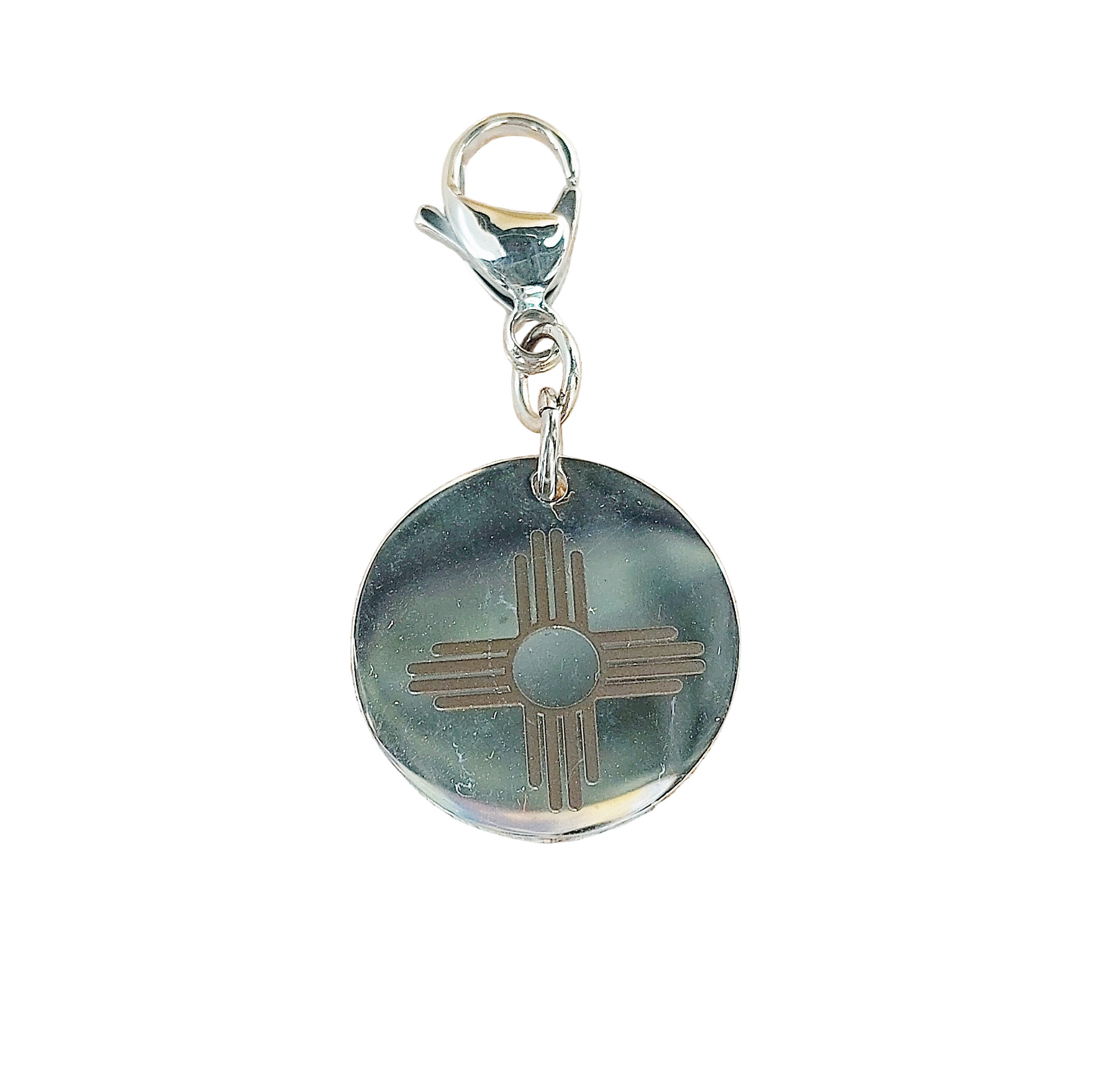 Round charm with a silver sun design on a white background