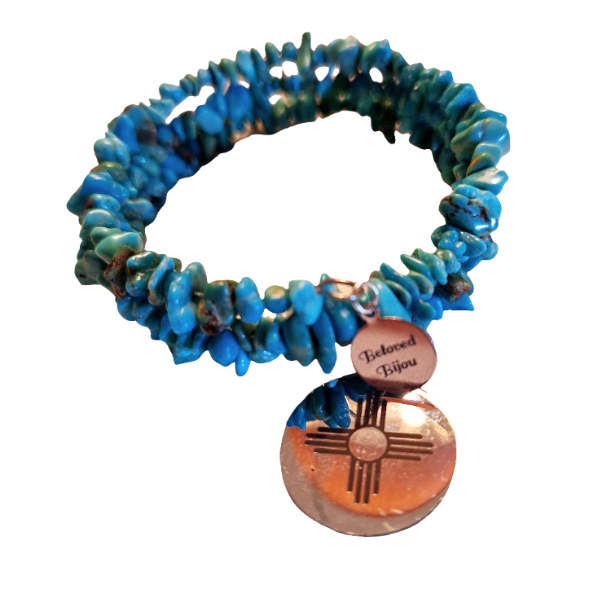 Turquoise bracelet with a zia sun charm on a white background
