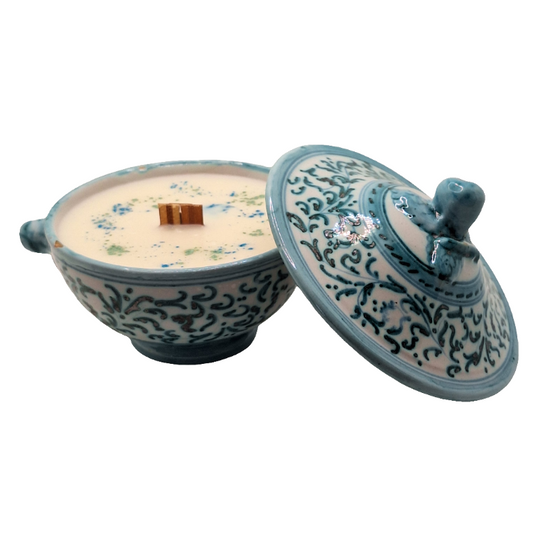 Ceramic container with lid featuring intricate blue patterns on a white background with a wood wick candle inside