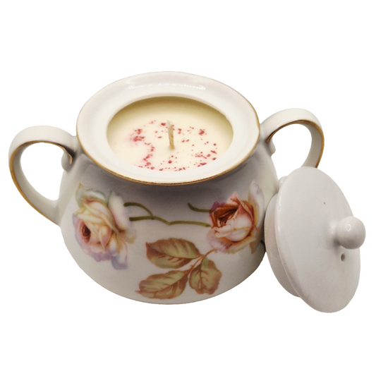 Decorative porcelain pot with floral design containing a candle.