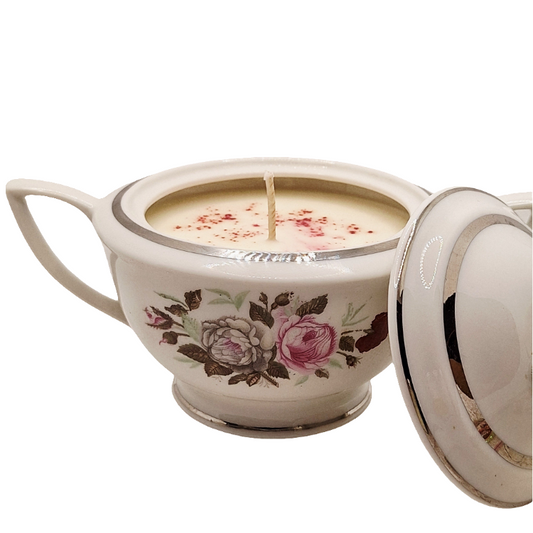 Decorative ceramic bowl with floral design containing a candle on a white background