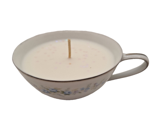 Candle in a teacup with floral design on a white background