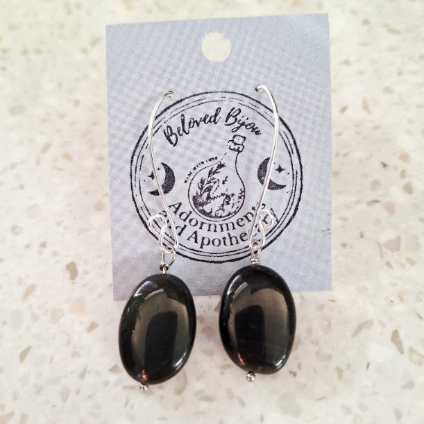 Black oval obsidian earrings on a branded card with a textured white background