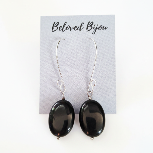 Black oval obsidian earrings on a Beloved Bijou card with a white background