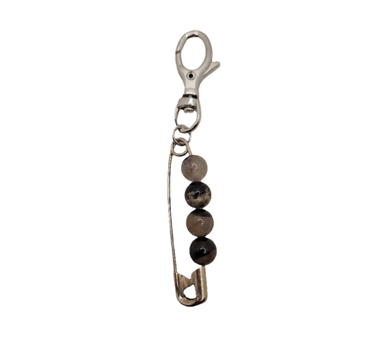 Metallic safety pin keychain with beads on a white background