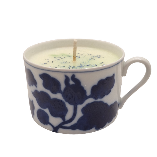 Candle in a blue and white floral-patterned mug on a white background