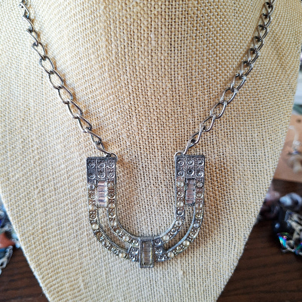 Silver horseshoe necklace on a mannequin bust with a neutral background