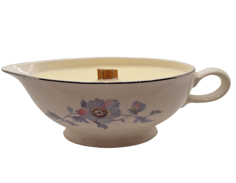 Ceramic gravy boat with floral design and a wood wick candle on a white background