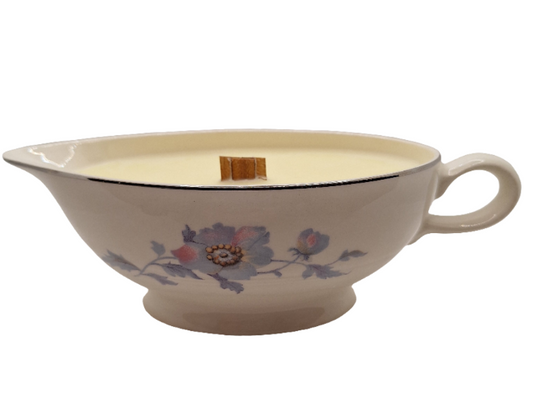 Ceramic gravy boat with floral design and a wood wick candle on a white background