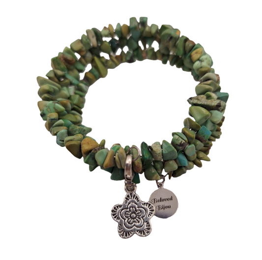 Green beaded bracelet with silver charms on a white background