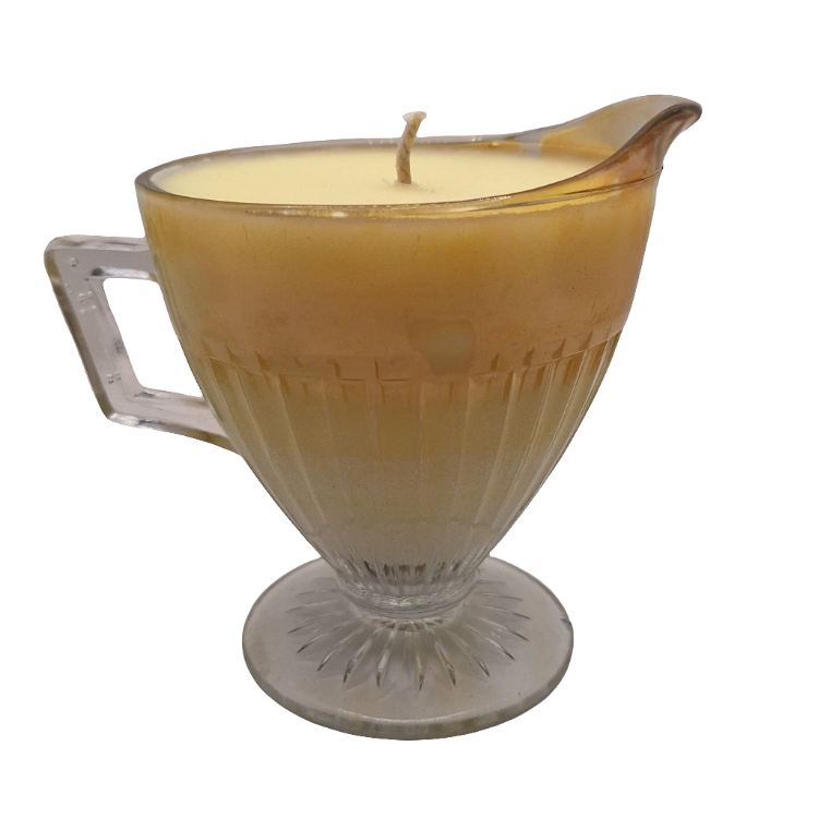 Candle in a glass milk pitcher with a handle on a white background