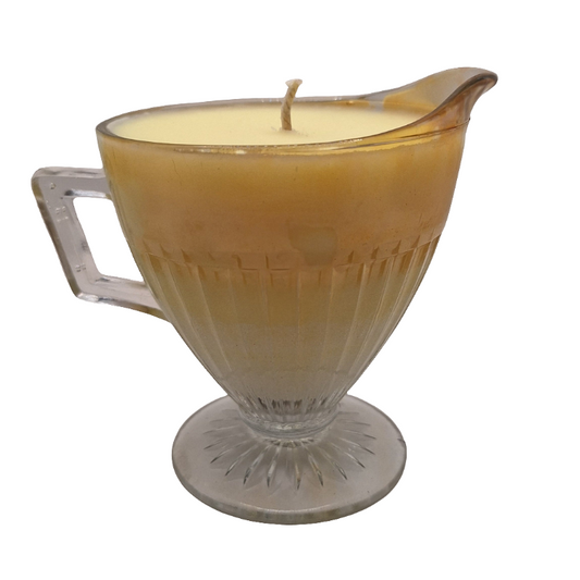Candle in a glass milk pitcher with a handle on a white background