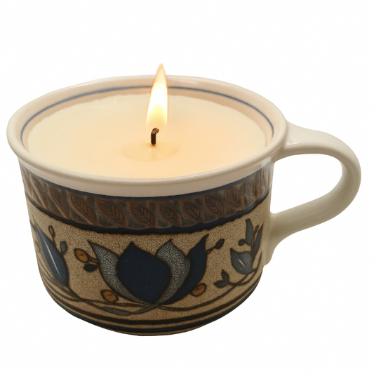 Ceramic mug with a lit candle inside on a white background